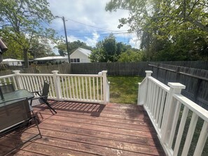 A wooden deck with white railings, a table, and chairs. - Cozy 2-bedroom house in pleasant Apalachicola with AC (Apalachicola)