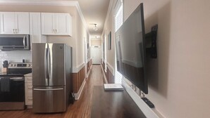 Eine moderne Küche mit Edelstahlgeräten, Holzboden und einem an der Wand befestigten Flachbildfernseher.