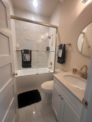 Een badkamer met een bad, toilet, wastafel en spiegel.