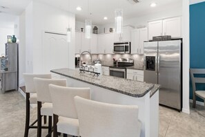 Eine moderne Küche mit weißen Schränken, Edelstahlgeräten, einer Granitabdeckung und Barhocker.