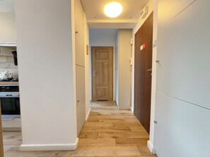 Ein schmaler Korridor mit Holzboden, weißen Wänden und einer Tür am Ende.