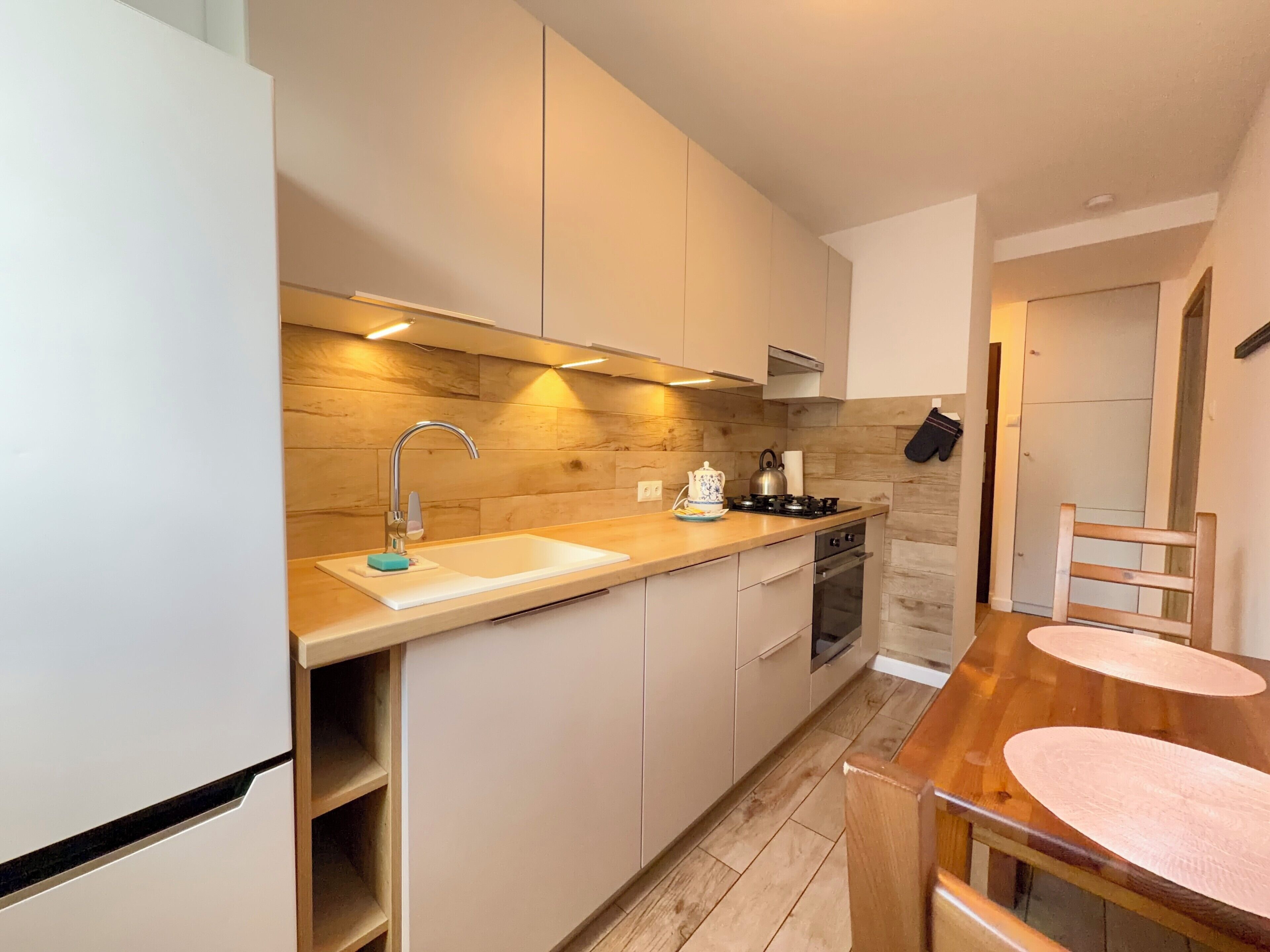 Eine moderne Küche mit Holzrückwand, Edelstahlgeräten und einem Holzesstisch mit Stühlen.