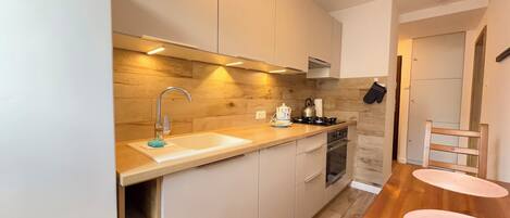 A modern kitchen with a wooden backsplash, stainless steel appliances, and a wooden dining table with chairs.