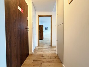 Ein Flur mit Holztüren, Holzboden und Blick in einen anderen Raum mit einem großen Holzschrank.