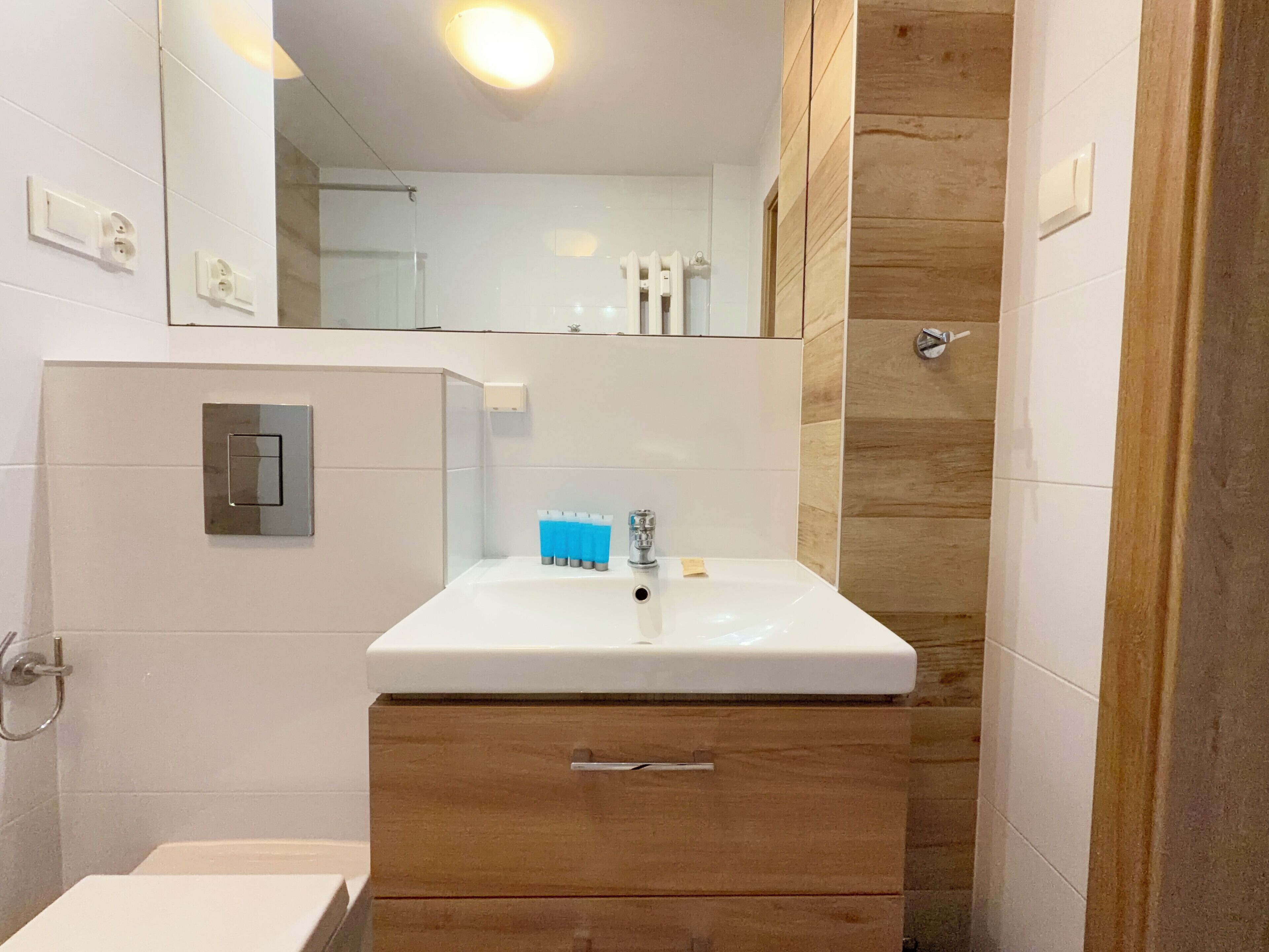 Ein Badezimmer mit einem weißen Waschbecken, einem Holzkorpus und einem Spiegel.