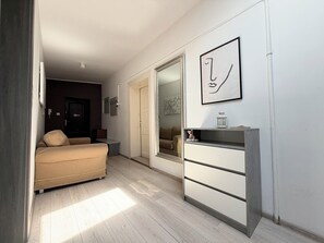 Une pièce comprenant un lit, une commode, un miroir et une porte donnant sur une autre pièce.