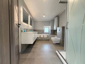 Un baño moderno con un tocador grande, un inodoro separado y una zona de ducha.
