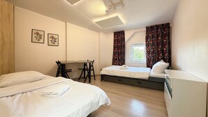 A hotel room with two beds, a desk, and a window with curtains. - Park Leśnicki Homely Studio #2 (Wrocław)