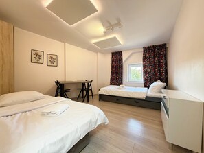Une chambre d’hôtel avec deux lits, un bureau et une fenêtre avec des rideaux.