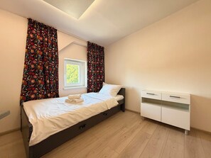 Un dormitorio con cama, ventana, mesita de noche y armario.