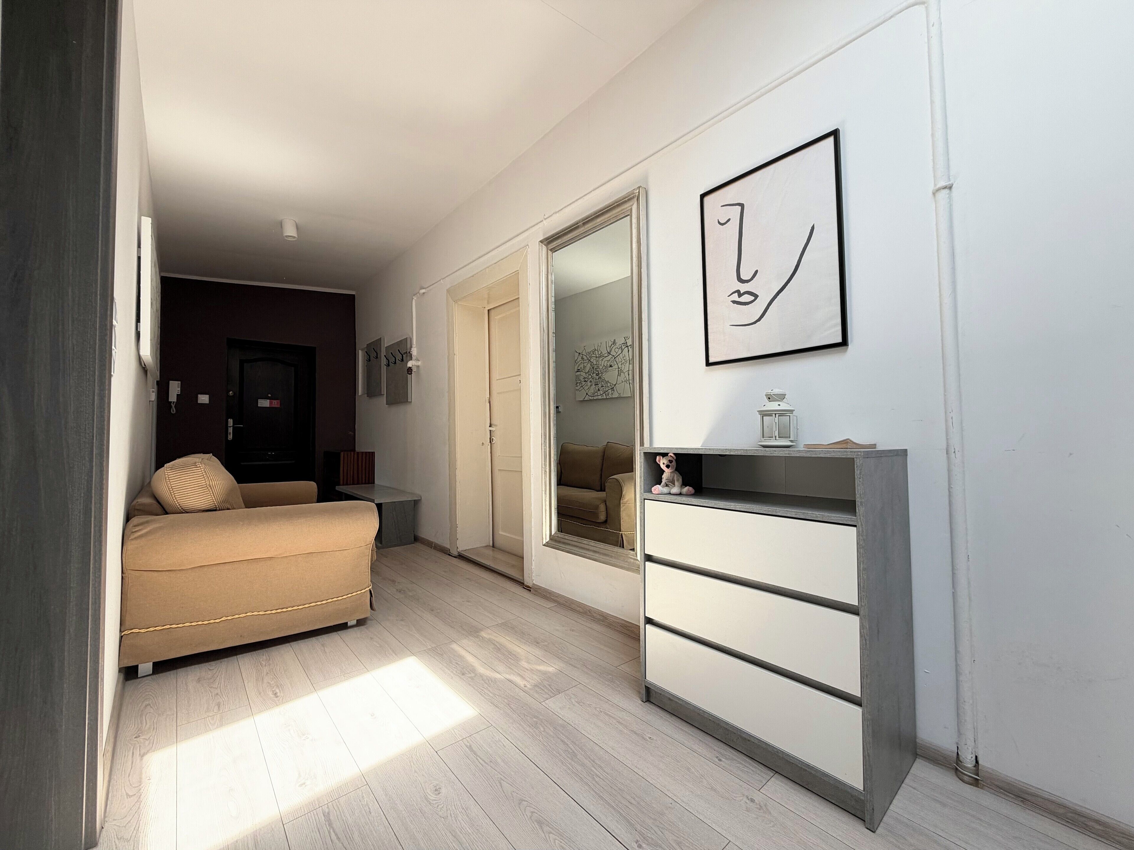Una habitación con cama, cómoda, espejo y una puerta que da a otra estancia.