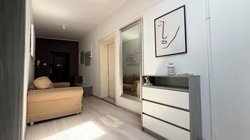 Una habitación con cama, cómoda, espejo y una puerta que da a otra estancia.