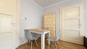 A small room with a wooden table, two chairs, a wall-mounted radiator, and a door. - Park Leśnicki Homely Studio #3 (Wrocław)