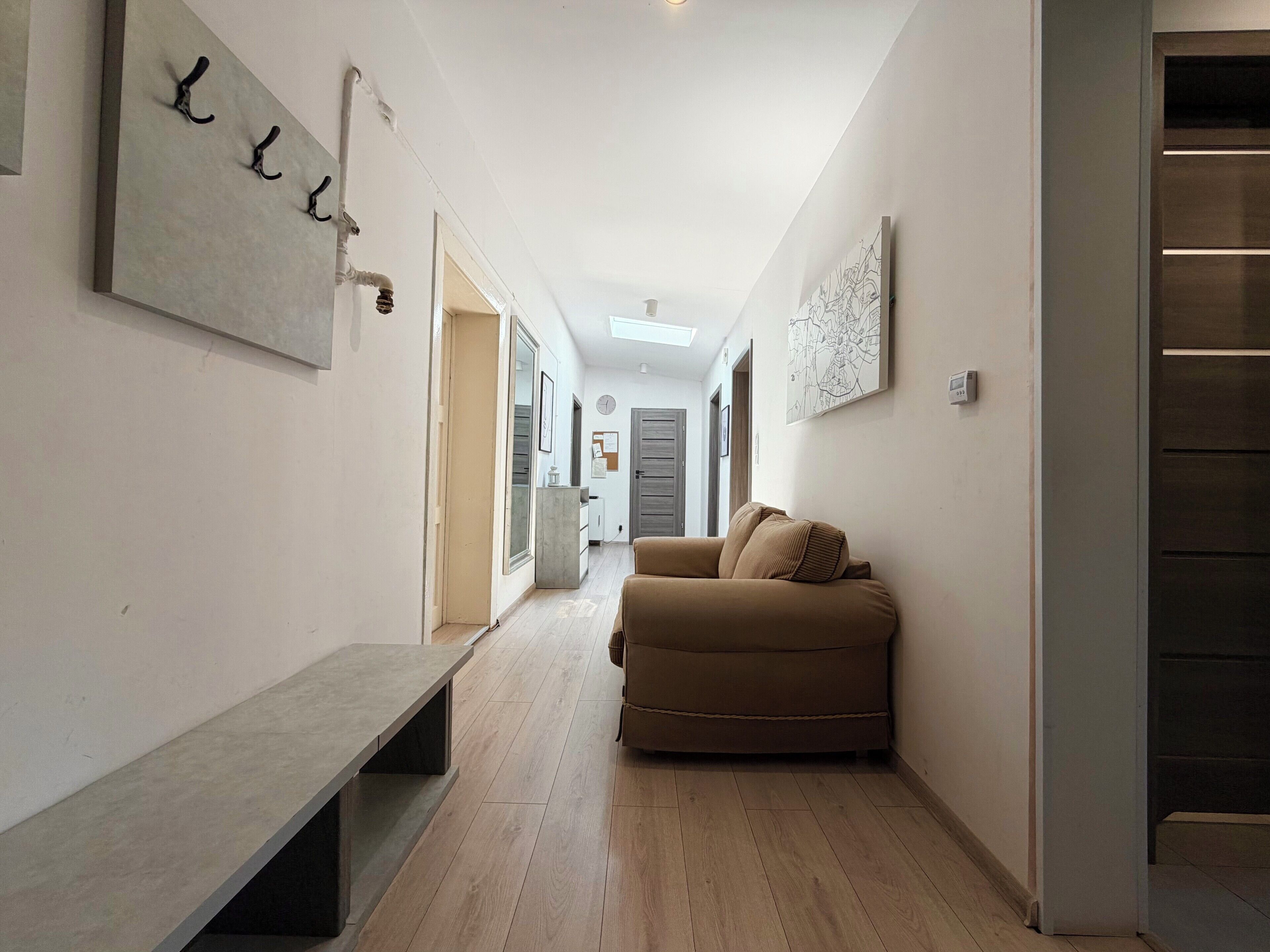 A hallway with a bench, a sofa, and a map on the wall.