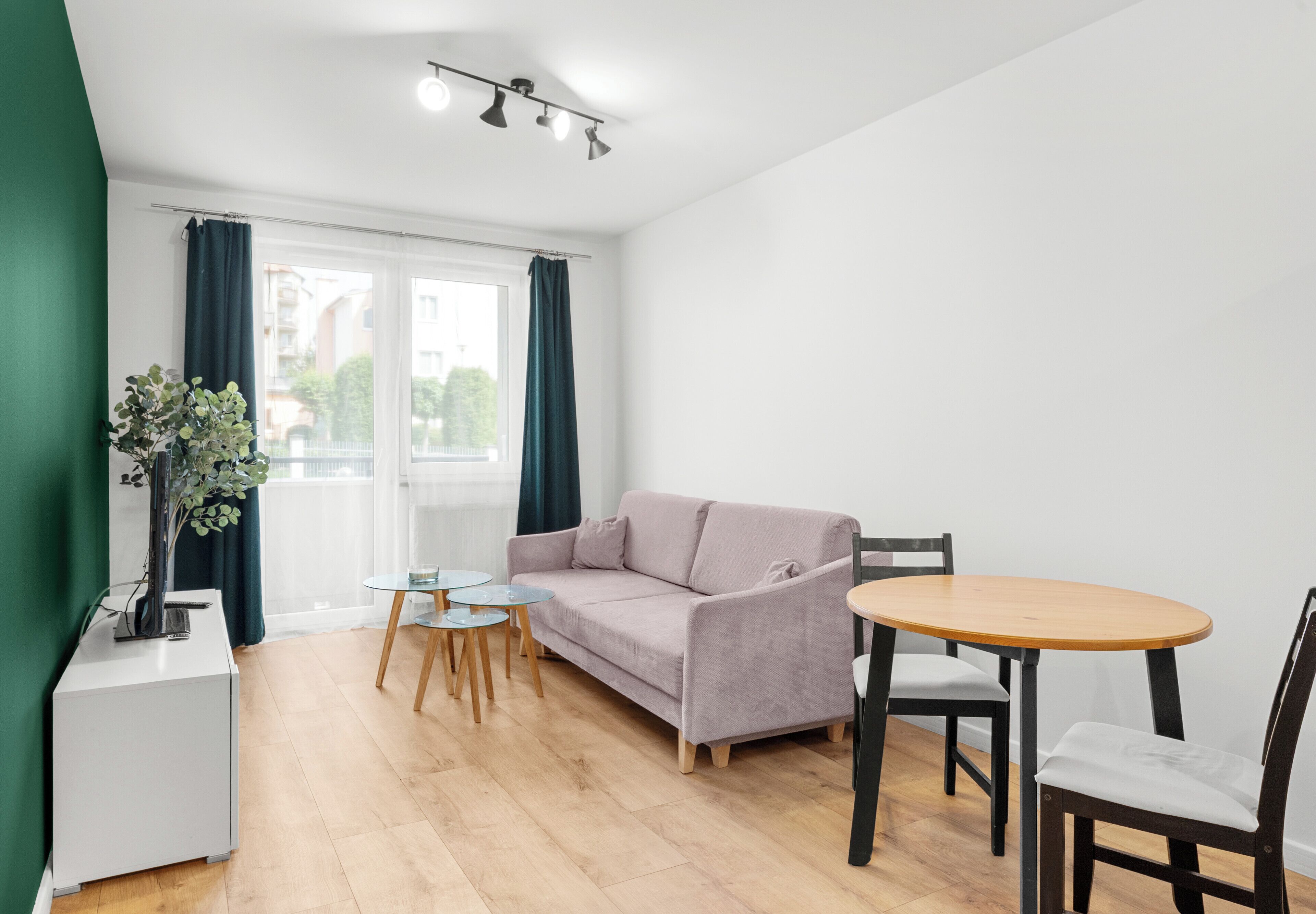 Una sala de estar moderna con un sofá, una mesa redonda de madera y una pequeña mesa auxiliar.