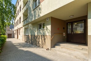 Ein mehrstöckiges Gebäude mit Eingang im Erdgeschoss, einer Treppe und einer Tür mit Glasfenster.