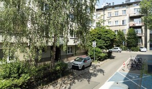 A residential street with parked cars, bicycles, and a building with multiple windows and balconies. - Sołtyka Comfort Apartment (Kraków)