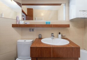 A modern bathroom with a wooden vanity, white sink, and a mirror above. - Sołtyka Comfort Apartment (Kraków)