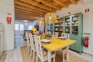 Ein Essbereich mit Holztisch, weißen Stühlen und hängenden Korbstühlen.