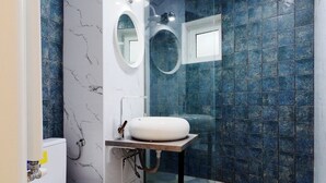 A bathroom with a toilet, a sink, a mirror, and a shower area. - City View Studio: Your Cozy Urban Retreat (Bucharest)