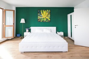 Une chambre avec un grand lit, une table de chevet, une lampe et un mur vert.