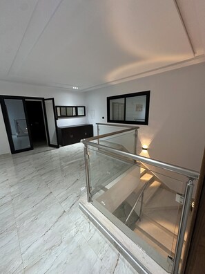 A spacious room with a glass railing, a dark wooden cabinet, and a framed picture on the wall. - Discover our magnificent Cercina villa, nestled in the heart of the tourist area (Sfax)