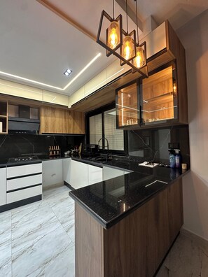 A modern kitchen with a central island, wooden cabinets, a black countertop, and pendant lighting. - Discover our magnificent Cercina villa, nestled in the heart of the tourist area (Sfax)