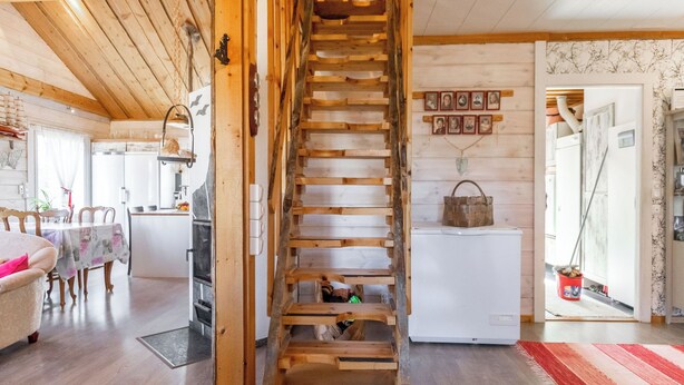 Un interno rustico con una scala in legno, un'area pranzo e una cucina.