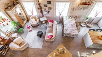 A spacious living area with a sofa, chairs, a dining table, and a staircase leading to an upper level.