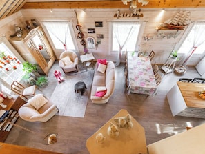 A spacious living area with a sofa, chairs, a dining table, and a staircase leading to an upper level.