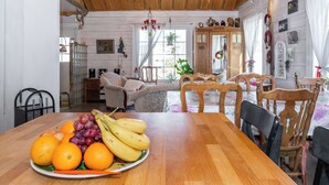 Un tavolo da pranzo in legno con un vassoio di frutta, una zona pranzo in legno e un angolo salotto accogliente con un divano e un armadio.