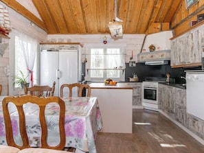 A kitchen with wooden cabinets, a central island, and a dining area with chairs and a table.