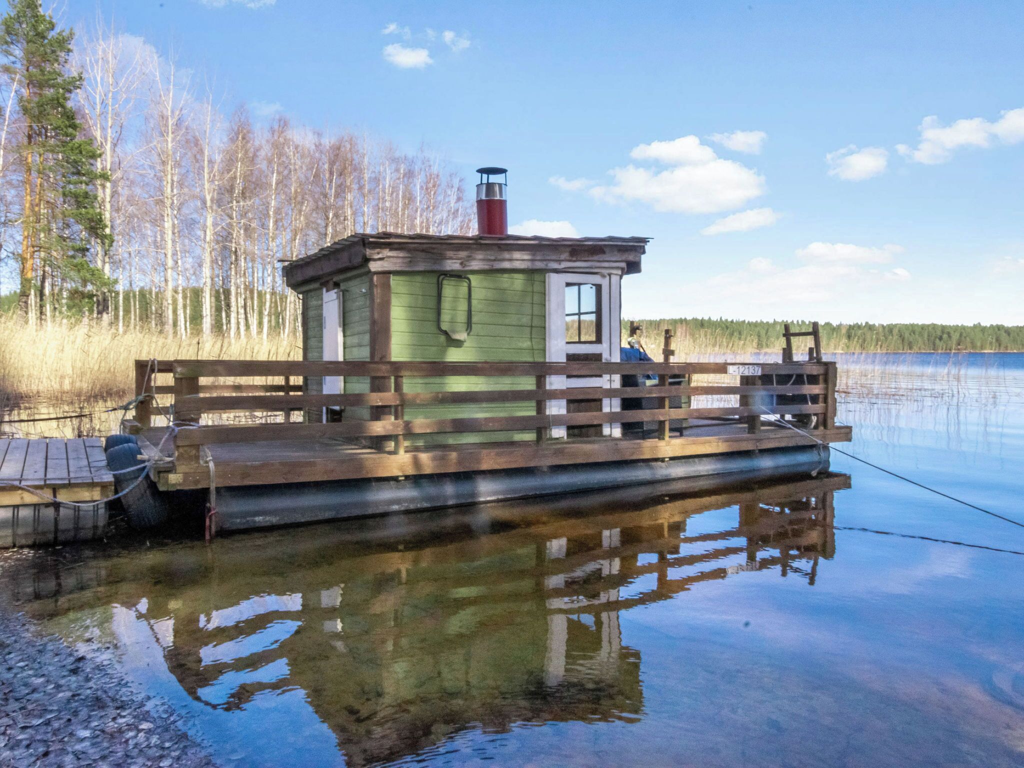Une jetée en bois avec une petite cabane, une canne à pêche et un lac paisible.