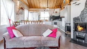Un soggiorno accogliente con camino, soffitto in legno e zona pranzo con cucina sullo sfondo.