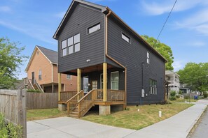 Ein zweistöckiges Haus mit Veranda, Treppe und einem sichtbaren Vorgarten.