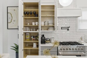 A kitchen with open cabinets, a stove, and various kitchen items. - Spacious Downtown Retreat, 4BR, Pool Table & Deck (Atlanta)