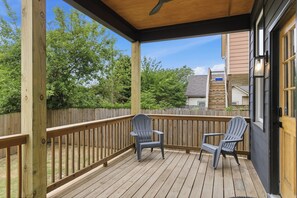 A wooden deck with two Adirondack chairs, a ceiling fan, and a view of a neighboring house. - Spacious Downtown Retreat, 4BR, Pool Table & Deck (Atlanta)