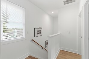 A clean, white-walled stairwell with a handrail, a window with blinds, and a framed picture on the wall. - Spacious Downtown Retreat, 4BR, Pool Table & Deck (Atlanta)