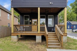 A two-story house with a wooden deck, a front porch, and a staircase leading to the entrance. - Spacious Downtown Retreat, 4BR, Pool Table & Deck (Atlanta)