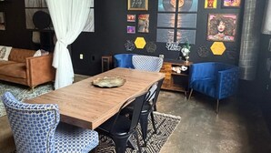 A dining area with a wooden table, patterned chairs, a blue sofa, and a wall decorated with framed pictures and hexagonal shapes.