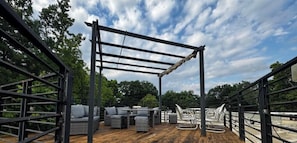 An outdoor deck with a metal pergola, wicker furniture, and a swing set.