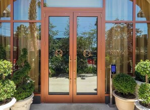 A hotel entrance with a glass door, a 'NoMad Residences' sign, and potted plants. - New Studio in Wynwood (Miami)