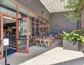 An outdoor cafe with tables and chairs, a glass door entrance, and a potted plant. - New Studio in Wynwood (Miami)