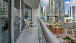 Ein Balkon mit weißem Stuhl, einem kleinen runden Tisch und einem Blumentopf.