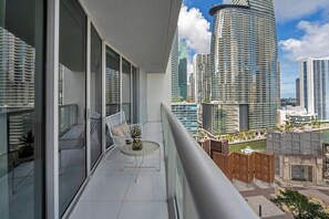 Ein Balkon mit weißem Stuhl, einem kleinen runden Tisch und einem Blumentopf.