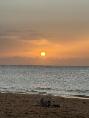 A beach with the sun setting over the ocean, a few bags and shoes on the sand, and a clear sky. - From the City to the Country. Close to beaches, restaurants, malls and more. (San Antonio)