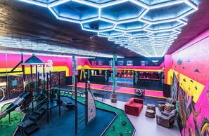 Un espace intérieur dynamique, doté d’un plafond à six pans, d’un espace de jeux et d’un coin salon avec une table de billard.