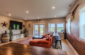 A spacious living area with a large TV, a fireplace, a dining area with a table and chairs, and a view of the outdoors.