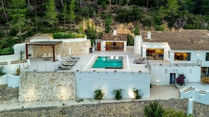 A modern villa with a swimming pool, stone walls, and a view of a forested hillside. - Caray - By Almarina Villas (BENISSA)
