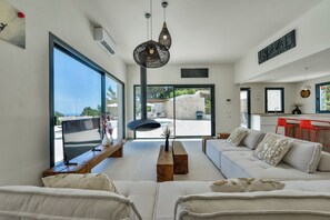 Ein modernes Wohnzimmer mit einer Couch, einem Couchtisch aus Holz und einer Pendelleuchte.
